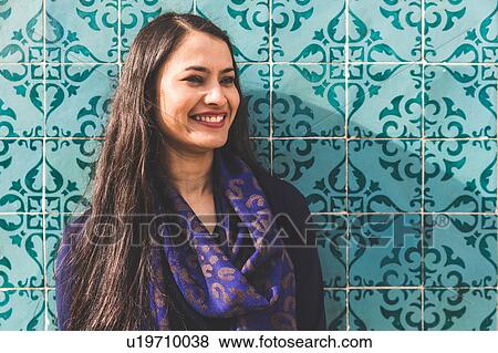 Stock Photo - Portrait of woman in front of colourful tiled wall, Lisbon, Portugal. Fotosearch