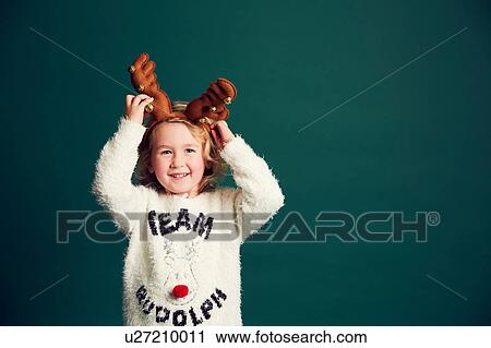 Stock Image - Portrait of young girl wearing Christmas and reindeer antlers. Fotosearch