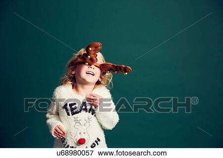 Stock Photo - Portrait of young girl wearing Christmas and reindeer antlers. Fotosearch