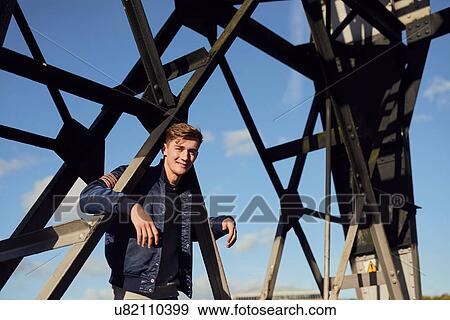 Portrait of young man, arms hooked around metal structure, Bristol, UK View Large Photo Image Stock Photo - Portrait of young man, arms hooked around metal structure, Bristol, UK. Fotosearch
