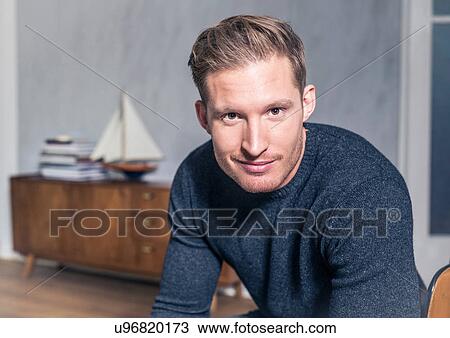 Stock Image - Portrait of young man in stylish living room. Fotosearch