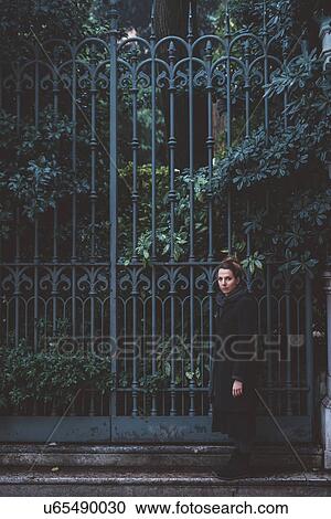 Stock Image - Portrait of young woman beside iron gates, Venice, Italy. Fotosearch