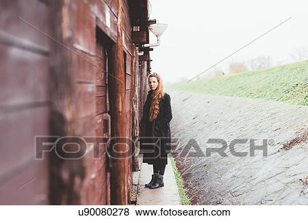 Portrait of young woman by weathered hut View Large Photo Image Stock Photo - Portrait of young woman by weathered hut. Fotosearch