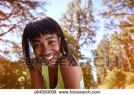 Portrait of young woman in rural setting, leaning towards camera, smiling View Large Photo Image Stock Photo - Portrait of young woman in rural setting, leaning towards camera, smiling. Fotosearch
