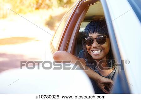 Stock Photograph - Portrait of young woman, looking out of car window. Fotosearch
