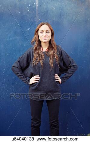Stock Photo - Portrait of young woman outdoors, hands on hips. Fotosearch