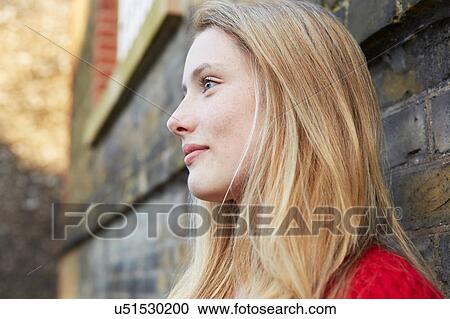 Stock Image - Portrait of young woman outdoors, looking away. Fotosearch