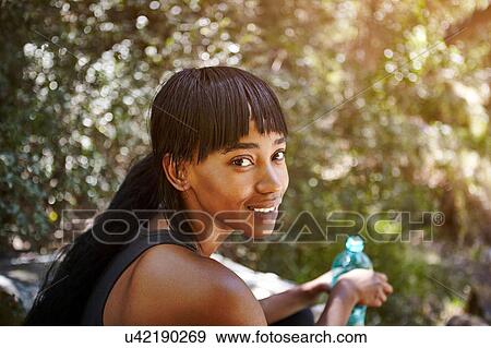 Stock Photo - Portrait of young woman outdoors, holding water bottle. Fotosearch