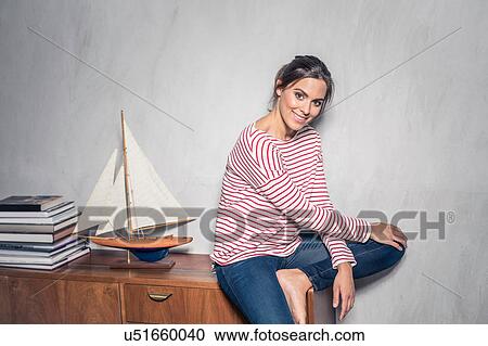 Portrait of young woman sitting on living room sideboard View Large Photo Image Stock Image - Portrait of young woman sitting on living room sideboard. Fotosearch