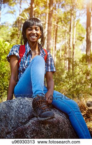 Stock Image - Portrait of young woman sitting on rock, Cape Town, South Africa. Fotosearch