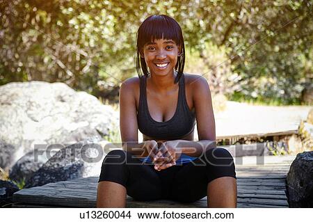 Picture - Portrait of young woman sitting outdoors, wearing sports clothing. Fotosearch