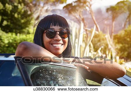 Portrait of young woman standing beside car, leaning on open car door View Large Photo Image Stock Photograph - Portrait of young woman standing beside car, leaning on open car door. Fotosearch