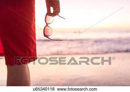 Rear cropped view of woman's hand holding sunglasses on beach at sunset, Nosara, Guanacaste Province, Costa Rica View Large Photo Image Stock Photo - Rear cropped view of woman's hand holding sunglasses on beach at sunset, Nosara, Guanacaste Province, Costa Rica. Fotosearch
