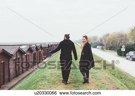 Rear view of couple strolling on embankment View Large Photo Image Stock Photograph - Rear view of couple strolling on embankment. Fotosearch