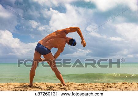 Rear view of muscular male swimmer on beach bending over sideways View Large Photo Image Stock Image - Rear view of muscular male swimmer on beach bending over sideways. Fotosearch