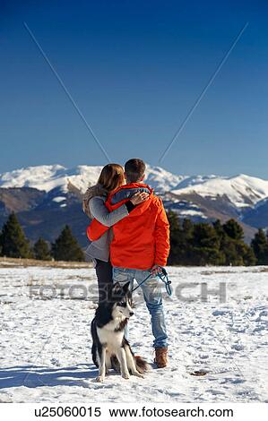 Rear view of romantic couple with dog looking out at snow covered mountain landscape View Large Photo Image Stock Photography - Rear view of romantic couple with dog looking out at snow covered mountain landscape. Fotosearch