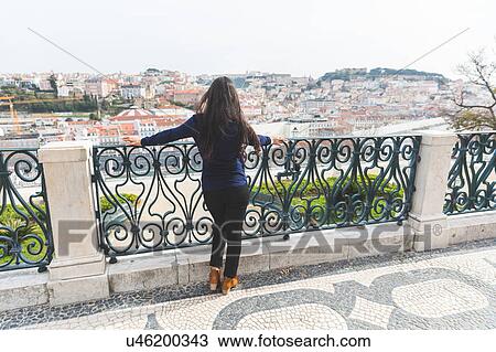 Stock Image - Rear view of woman looking away at elevated view of Lisbon, Portugal. Fotosearch