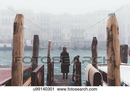 Rear view of woman looking out from misty canal pier, Venice, Italy View Large Photo Image Stock Image - Rear view of woman looking out from misty canal pier, Venice, Italy. Fotosearch