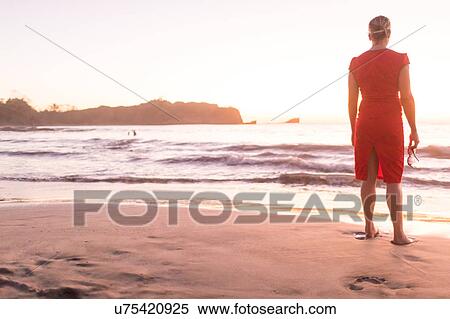 Rear view of woman looking out to sea from beach at sunset, Nosara, Guanacaste Province, Costa Rica View Large Photo Image Stock Photography - Rear view of woman looking out to sea from beach at sunset, Nosara, Guanacaste Province, Costa Rica. Fotosearch