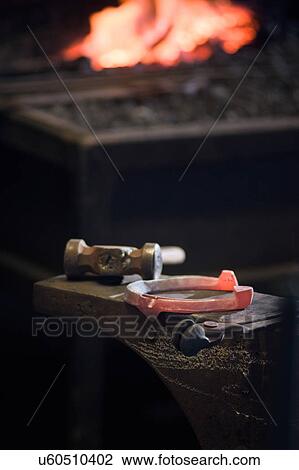 Stock Image - Red hot horseshoe on anvil. Fotosearch