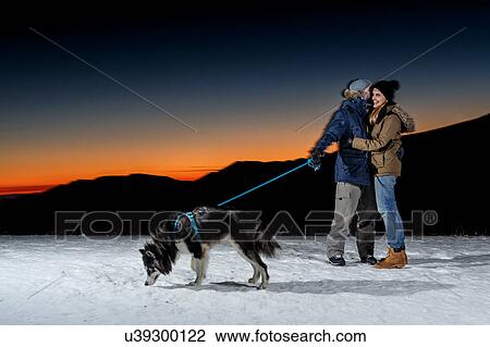 Romantic couple with dog in snow at night View Large Photo Image Stock Image - Romantic couple with dog in snow at night. Fotosearch