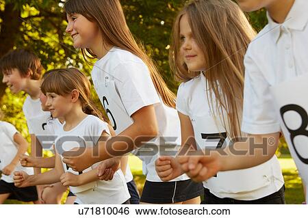 Stock Photograph - Row of boys and girls on race starting line on playing field. Fotosearch