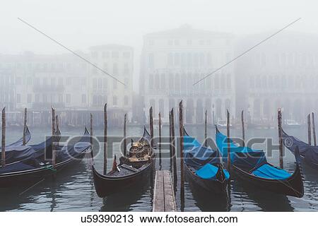 Stock Image - Rows of gondolas on misty canal, Venice, Italy. Fotosearch