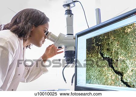Stock Photography - Scientist inspecting metal surface with microscope in laboratory. Fotosearch