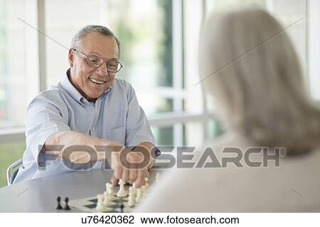 Stock Image - Senior couple playing chess. Fotosearch