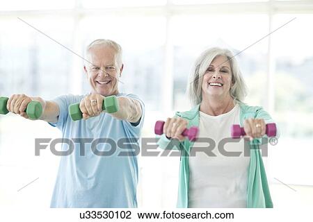 Stock Image - Senior couple using hand weights. Fotosearch