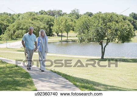Stock Image - Senior couple walking on path. Fotosearch