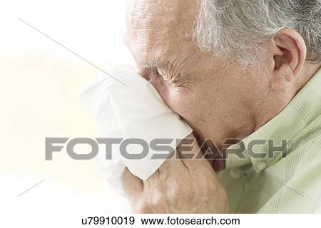 Stock Photo - Senior man blowing nose on tissue. Fotosearch