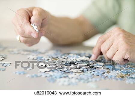 Stock Image - Senior man doing a jigsaw puzzle. Fotosearch