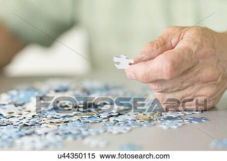 Stock Photography - Senior man doing a jigsaw puzzle. Fotosearch