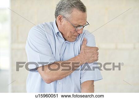 Stock Image - Senior man holding his left arm in pain. Fotosearch