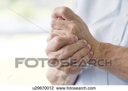 Senior man holding painful hand View Large Photo Image Stock Image - Senior man holding painful hand. Fotosearch