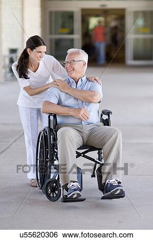 Stock Photograph - Senior man in wheelchair with care worker. Fotosearch