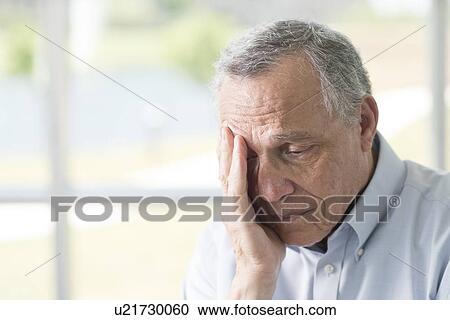 Stock Image - Senior man rubbing face. Fotosearch