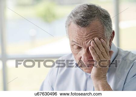Stock Photograph - Senior man rubbing face. Fotosearch