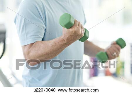 Stock Image - Senior man using weights. Fotosearch