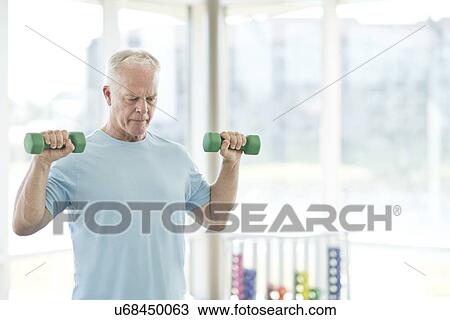 Stock Image - Senior man using weights. Fotosearch