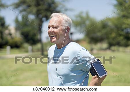Senior man wearing smartphone and earphones View Large Photo Image Stock Image - Senior man wearing smartphone and earphones. Fotosearch