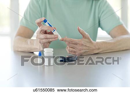 Stock Photography - Senior woman doing finger prick test. Fotosearch