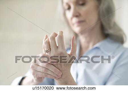 Stock Image - Senior woman holding painful hand. Fotosearch