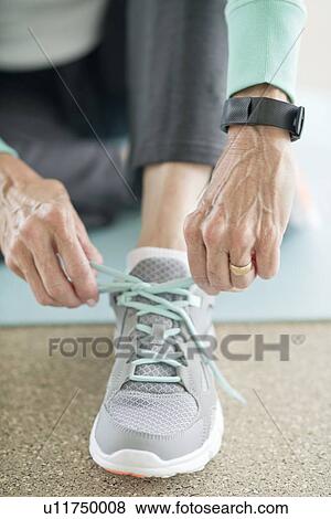 Stock Photo - Senior woman lacing up trainer. Fotosearch