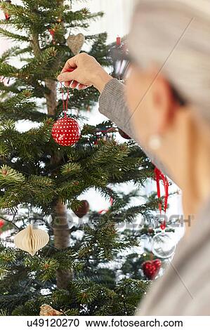 Senior woman putting bauble on christmas tree View Large Photo Image Stock Image - Senior woman putting bauble on christmas tree. Fotosearch