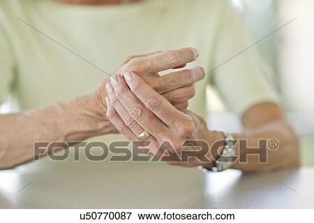 Stock Photo - Senior woman rubbing painful hand. Fotosearch