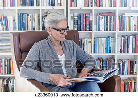 Senior woman sitting in chair in library, reading book View Large Photo Image Stock Image - Senior woman sitting in chair in library, reading book. Fotosearch