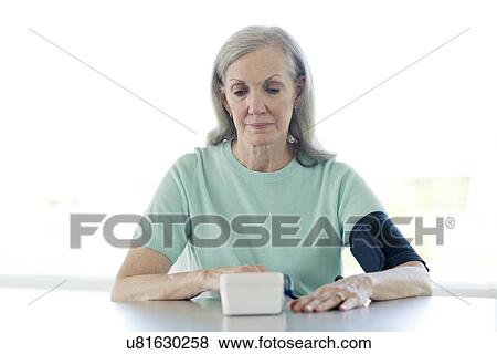 Senior woman taking her own blood pressure View Large Photo Image Stock Photo - Senior woman taking her own blood pressure. Fotosearch