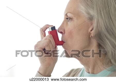 Stock Image - Senior woman using inhaler. Fotosearch